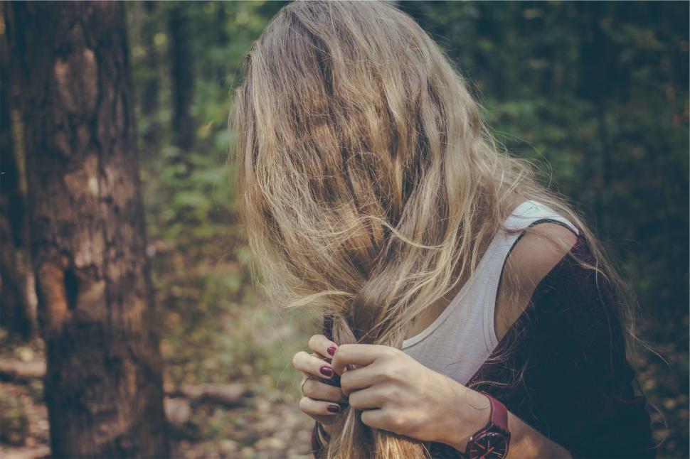 Free Image of Woman braiding her hair in a serene forest setting 