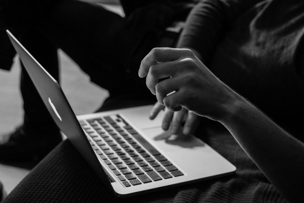Free Image of Person working on a laptop indoors in black and white 