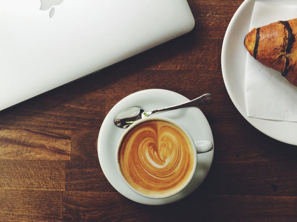 Free Image of Cup of latte coffee and a croissant on a wooden table 