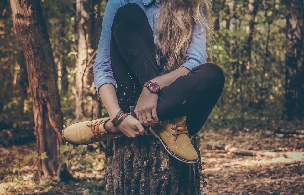 Free Image of Woman sitting on tree stump in forest with casual wear 