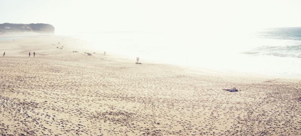 Free Image of Sunny beach with scattered people under bright sunlight. 