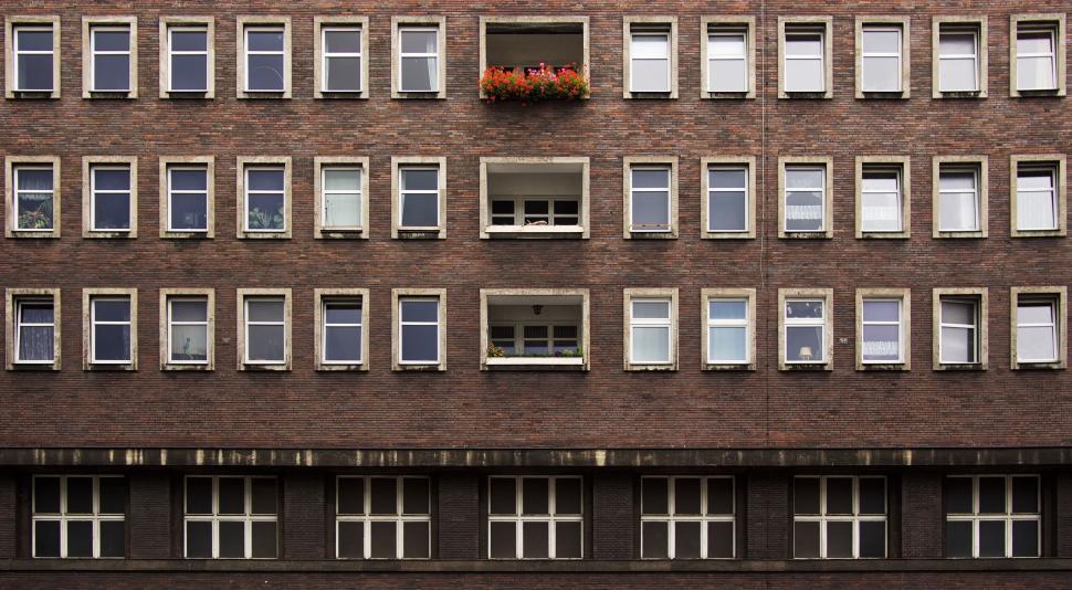 Free Image of Brick facade with many windows and flower planter above 