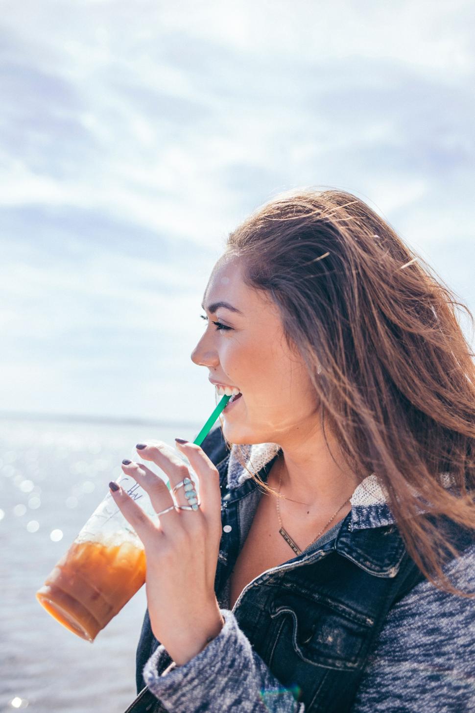 Free Image of Woman holding iced coffee on a sunny day outdoors 