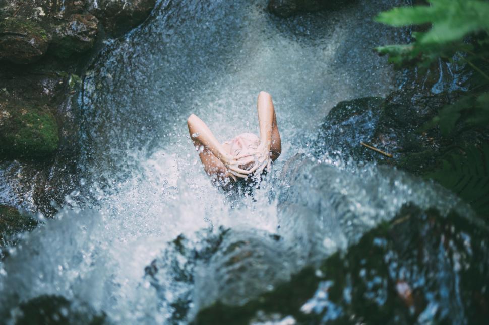 Free Image of Person enjoying waterfall with water splashing around 