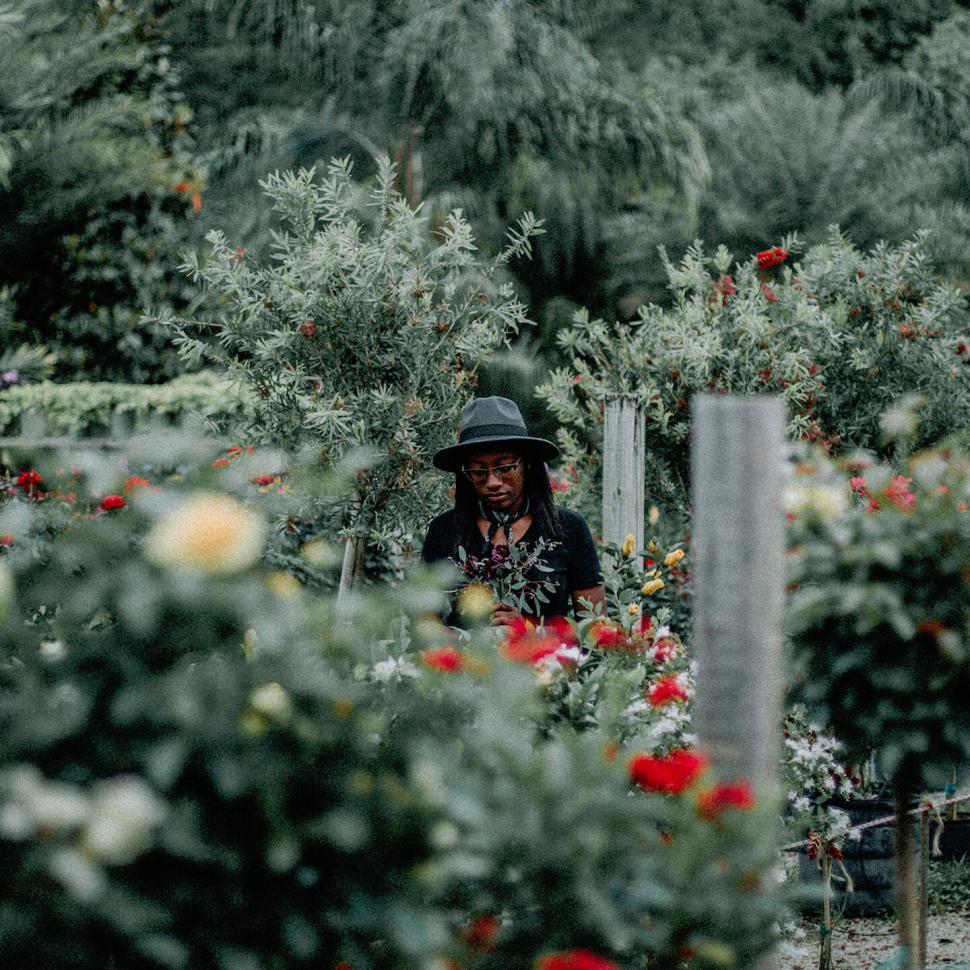 Free Image of Woman stands in garden surrounded by vibrant flowers. 
