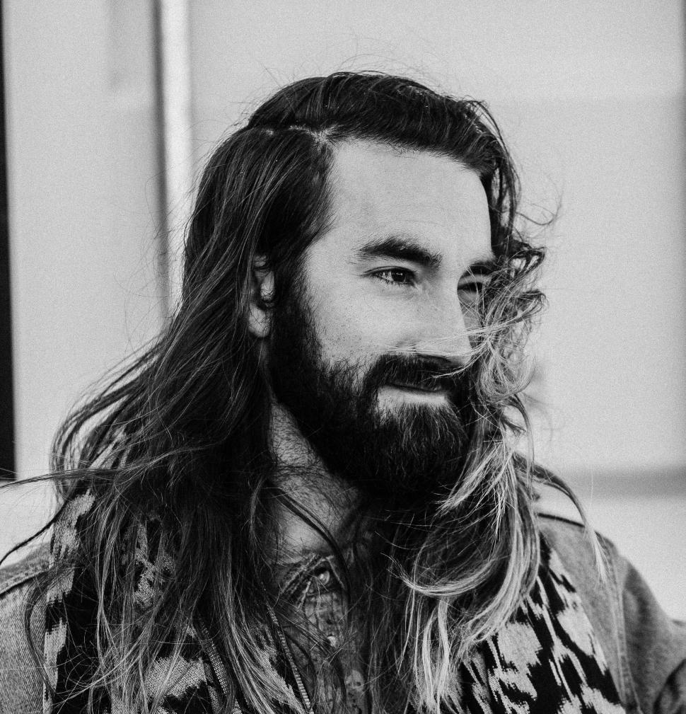 Free Image of Bearded man with long hair gazing thoughtfully outdoors. 