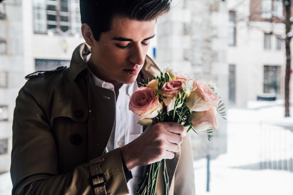 Free Image of Man holding bouquet of flowers on snowy, urban street. 