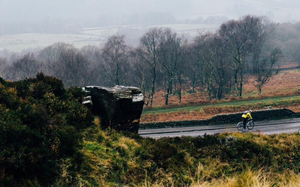 Free Image of Cyclist in yellow jacket riding through misty landscape. 
