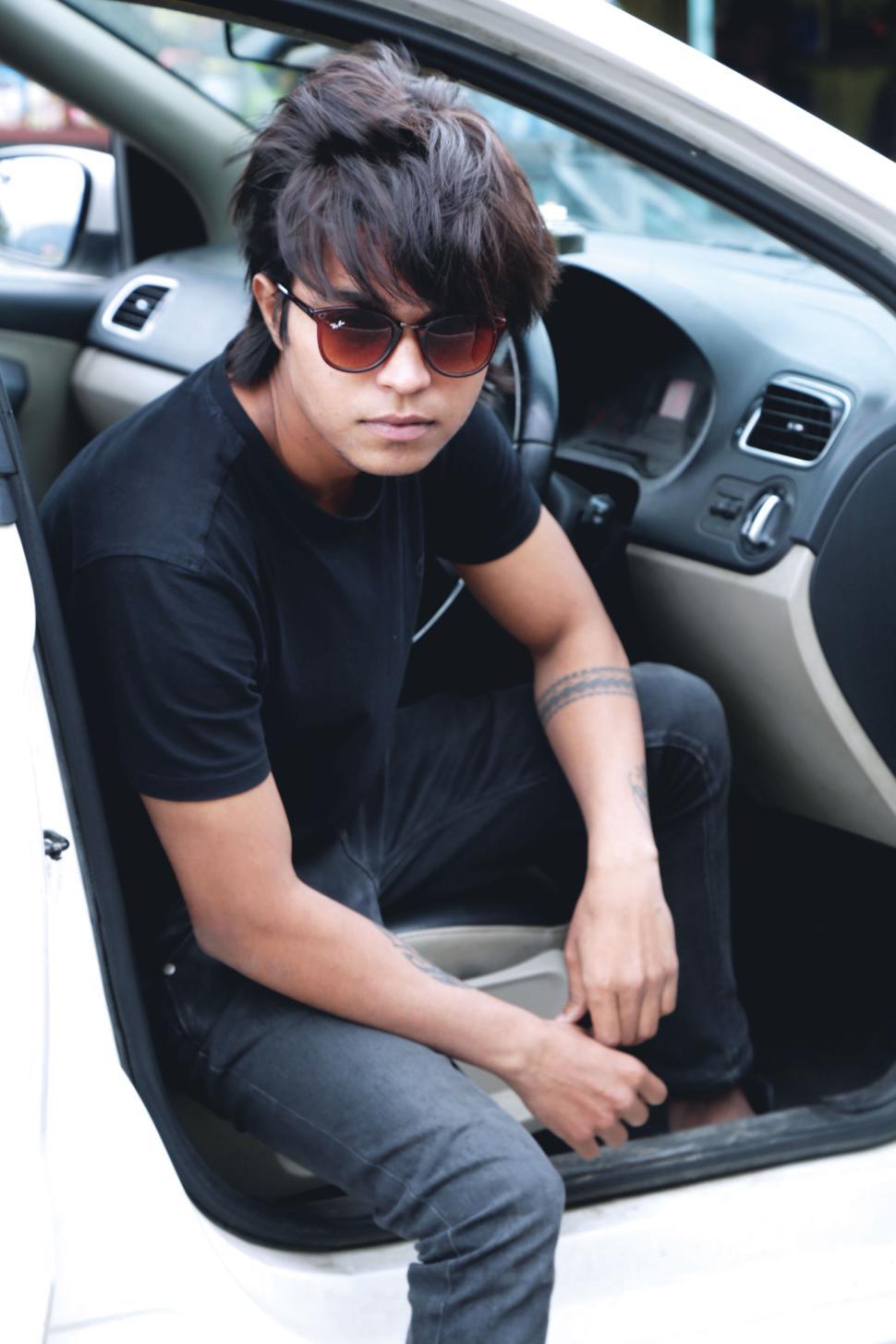 Free Image of Man sitting in car wearing sunglasses with cool hairstyle 