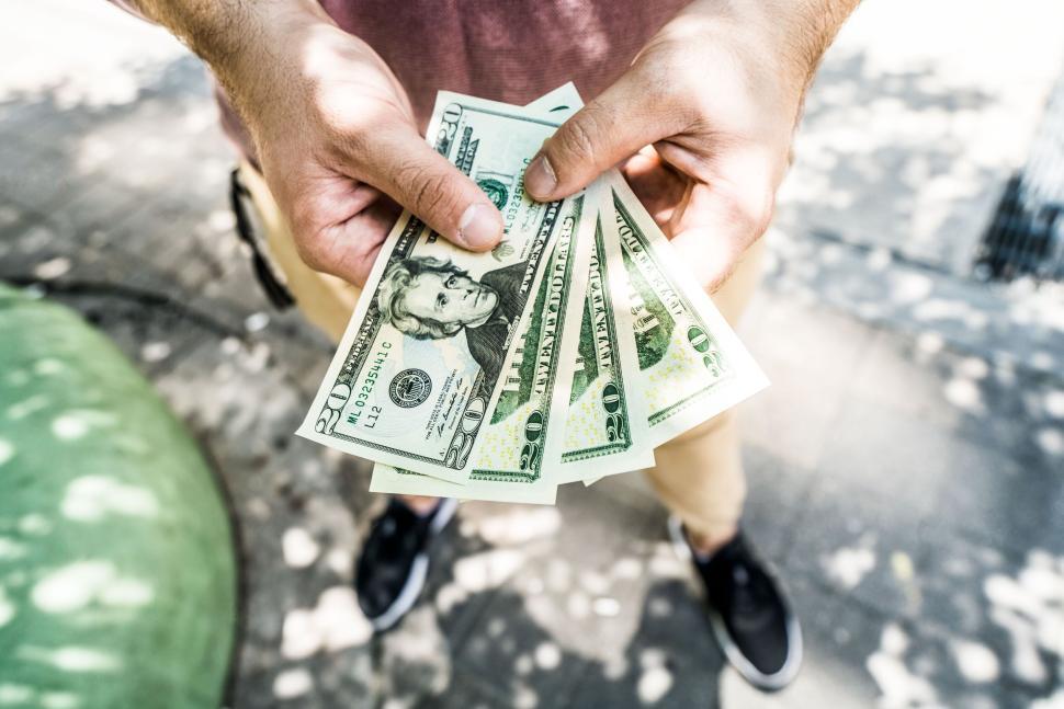 Free Image of Person holding fanned-out US dollar bills on the street 
