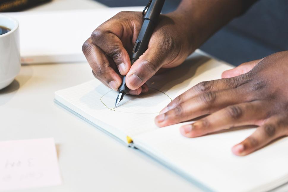 Free Image of Close-up of person drawing in notebook with pen 