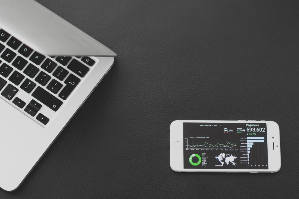 Free Image of Laptop half closed and smartphone showing analytics 