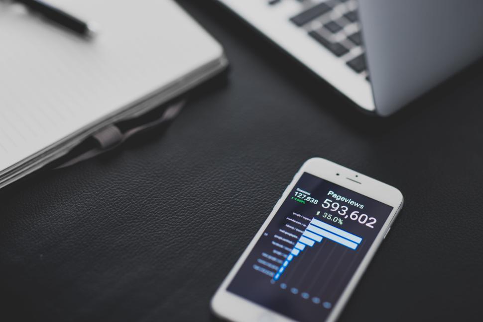 Free Image of Smartphone with analytics next to notebook on desk 