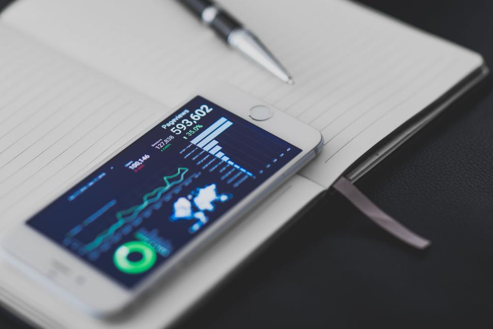 Free Image of Smartphone with analytics on notebook with pen 