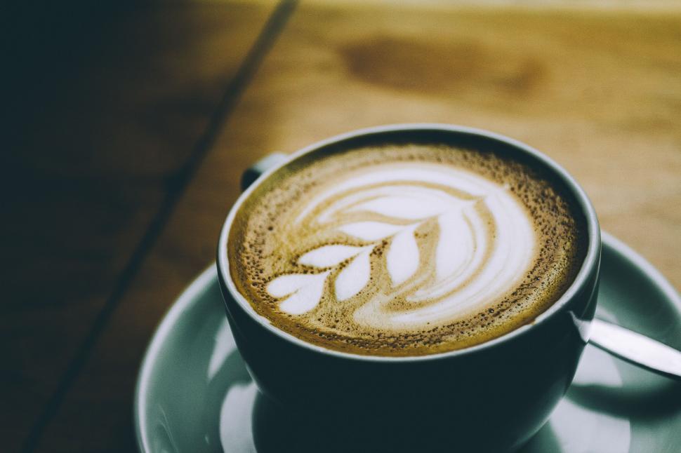 Free Image of Latte art with leaf design in a white coffee cup on table 