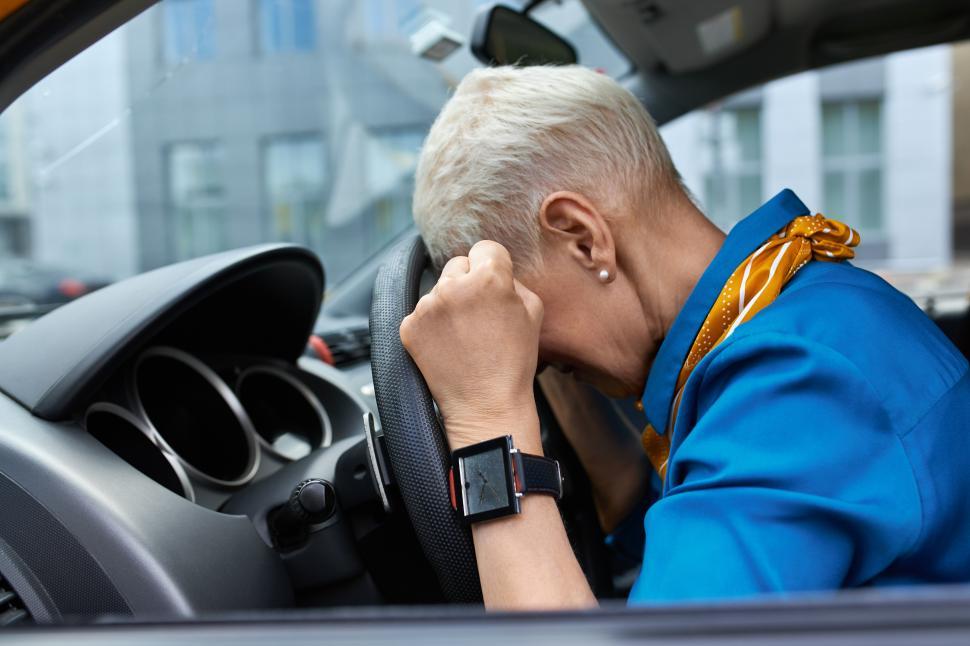 Free Image of Side view of unhappy stressed middle aged woman squeezing fists and resting head on steering wheel, stuck in traffic jam, being late for work or get into car accident, sitting in driver s seat 