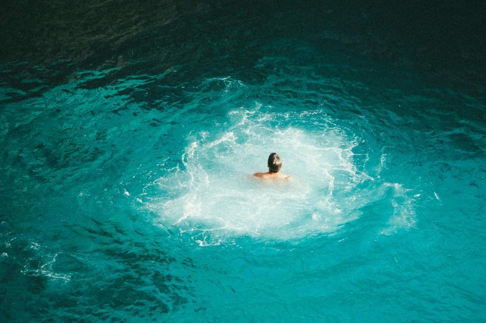 Free Image of Person swimming in clear aqua blue water from above 