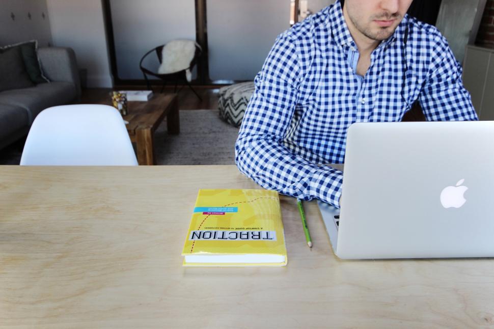 Free Image of Man working at desk with laptop and book, modern interior. 