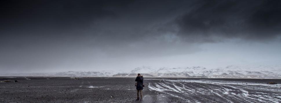 Free Image of Vast landscape with a lone person walking, overcast sky. 