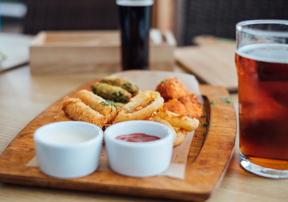 Free Image of Assortment of appetizers with beer on wooden platter at bar 
