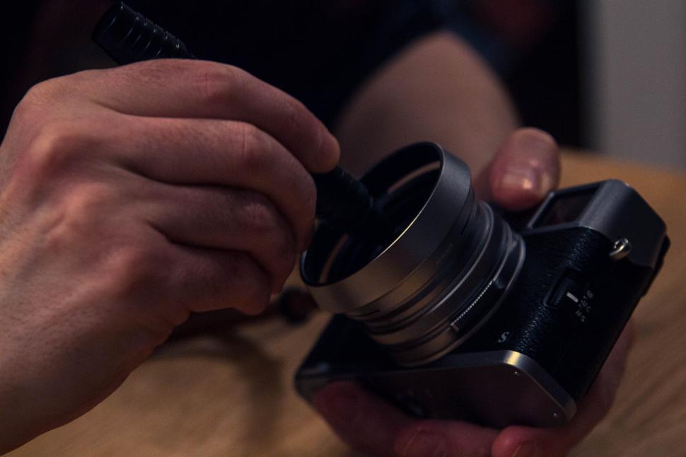 Free Image of Person cleaning camera lens with a small brush tool 