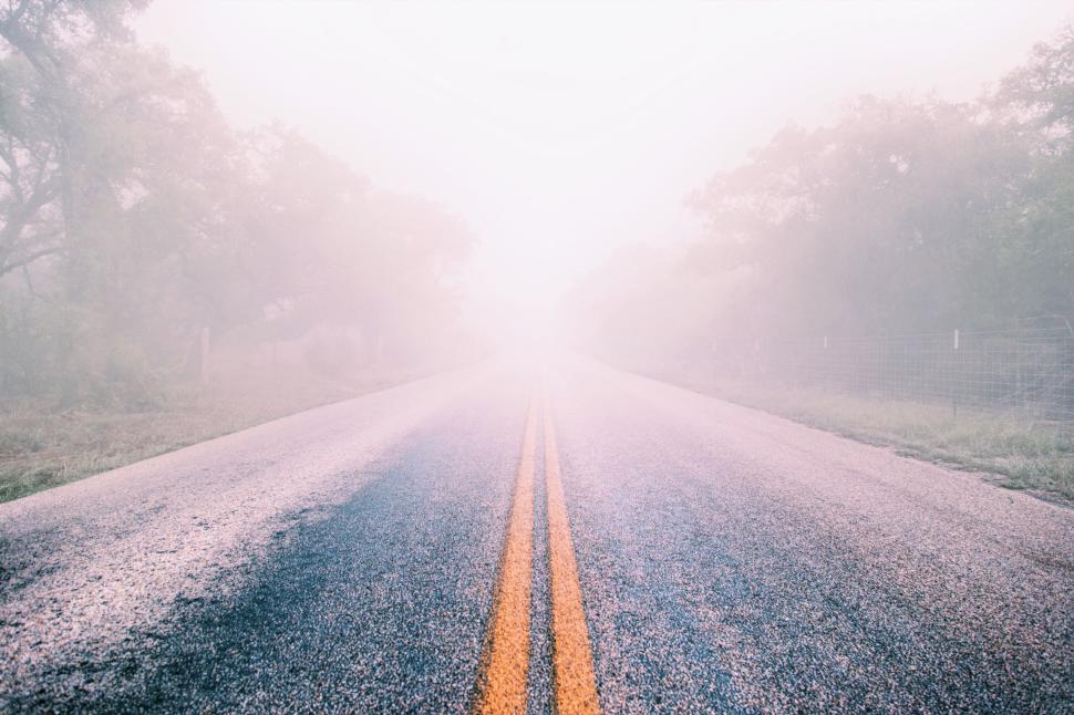 Free Image of Foggy road leading into the distance with yellow lines 