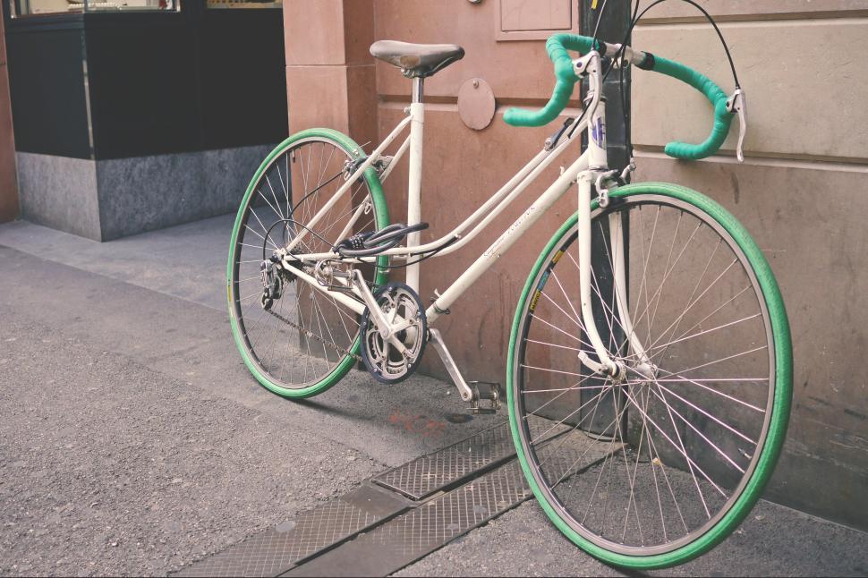 Free Image of White bike with green accents locked to a street pole 