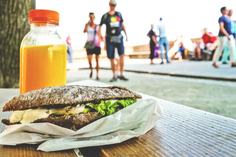 Free Image of Fresh sandwich and orange juice on outdoor table 