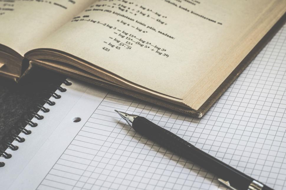 Free Image of Open math textbook with a pen and graph paper nearby 