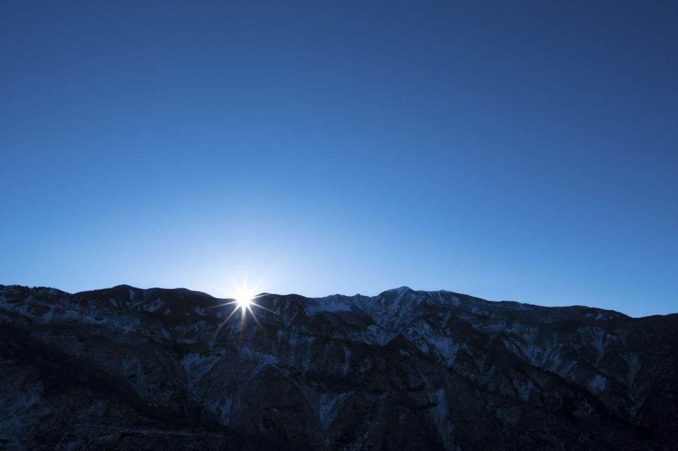 Free Image of Sunrise peeks over mountains creating a silhouette effect 