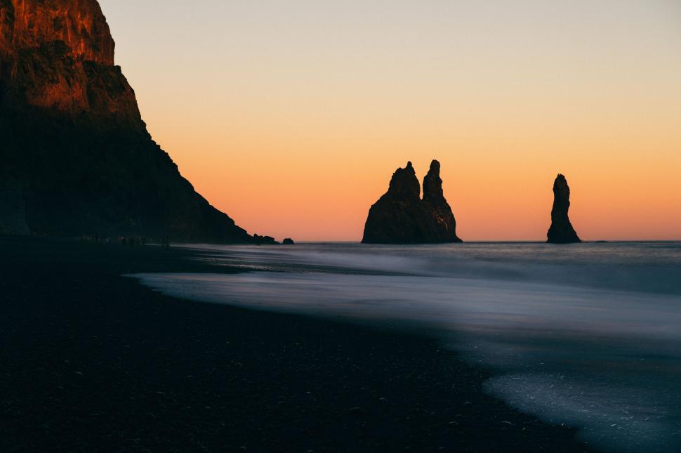 Free Image of Black sand beach with rock formations during sunset. 