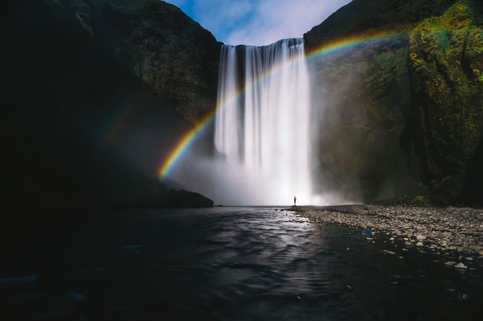 Free Image of Waterfall with rainbow over rocky landscape midday. 