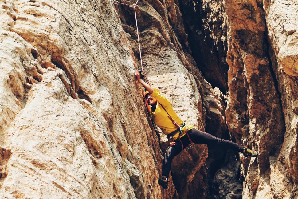 Free Image of Rock climber in action scaling a steep rocky cliff 