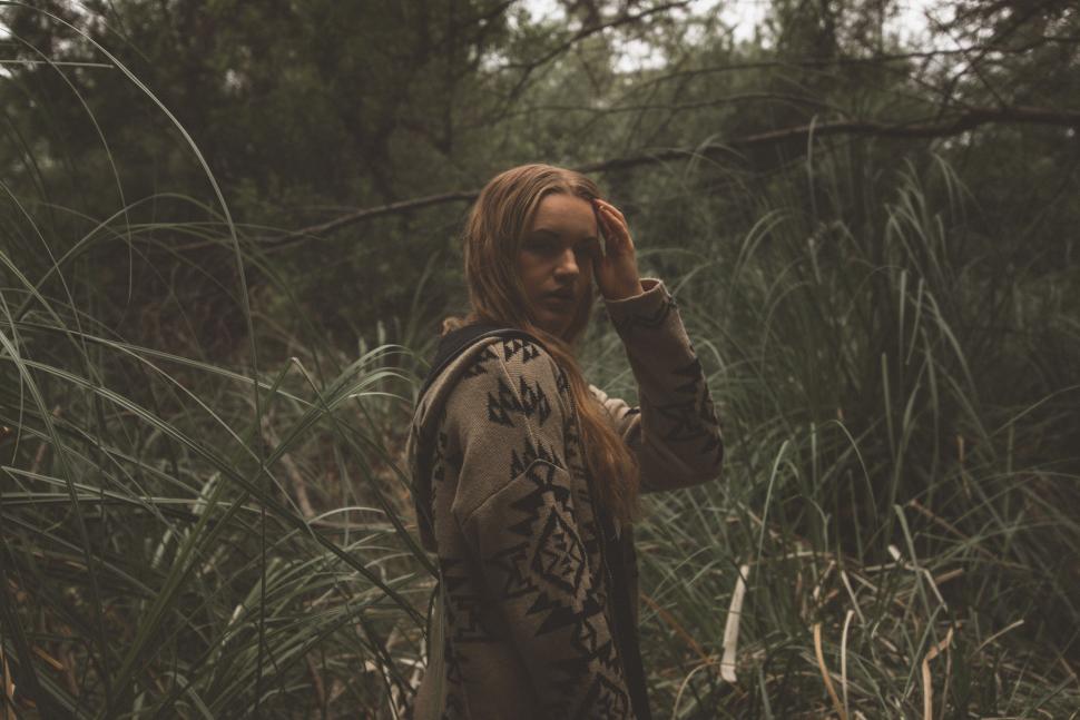 Free Image of Pensive woman standing amidst dense green tall grass 