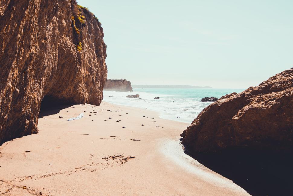 Free Image of Secluded beach with rocky formations and calm waves. 