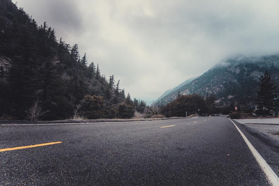 Free Image of Empty highway stretching through misty mountain forest. 