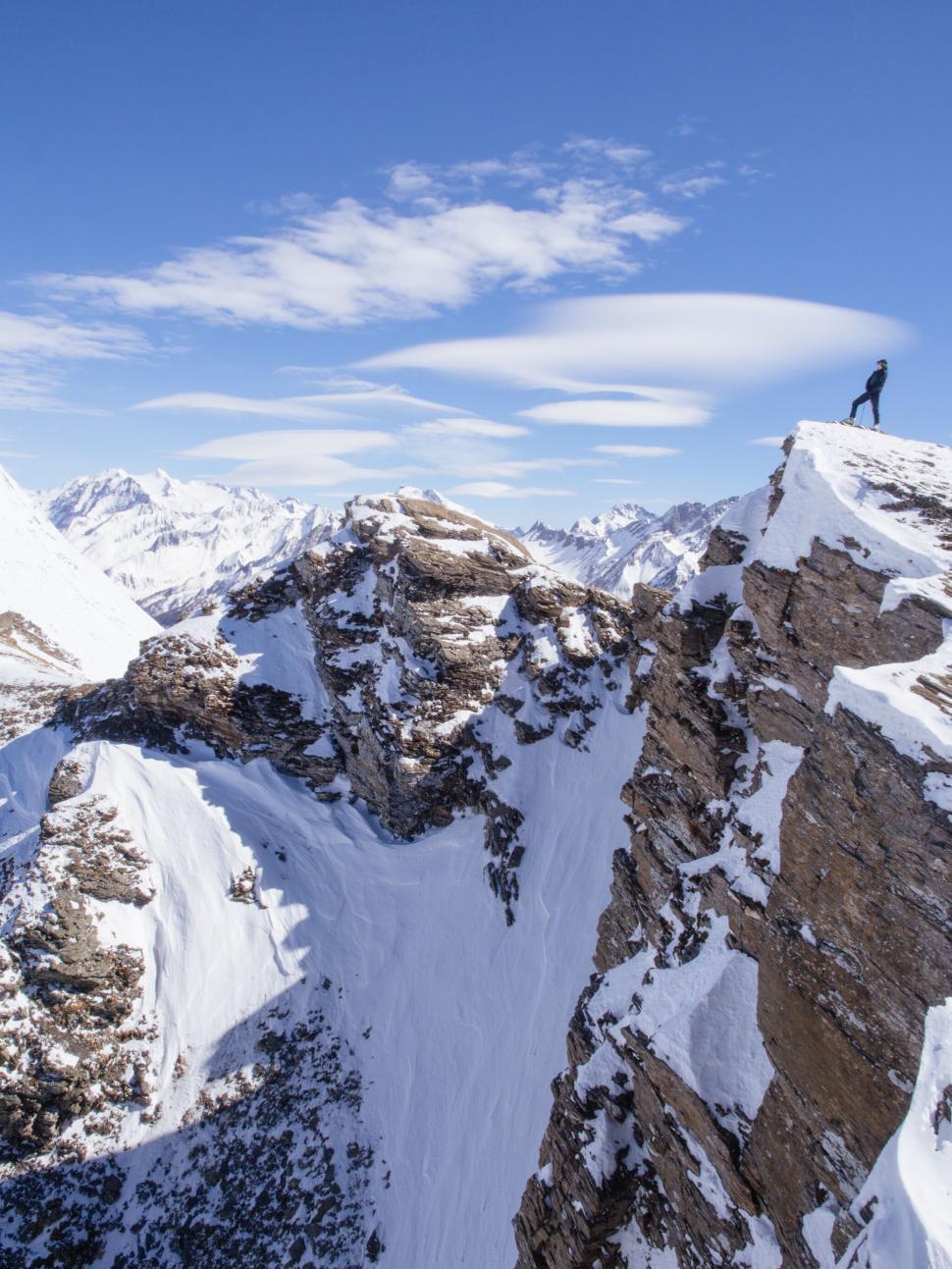 Free Image of Person Standing on Snowy Mountain Peak with Clear Sky 