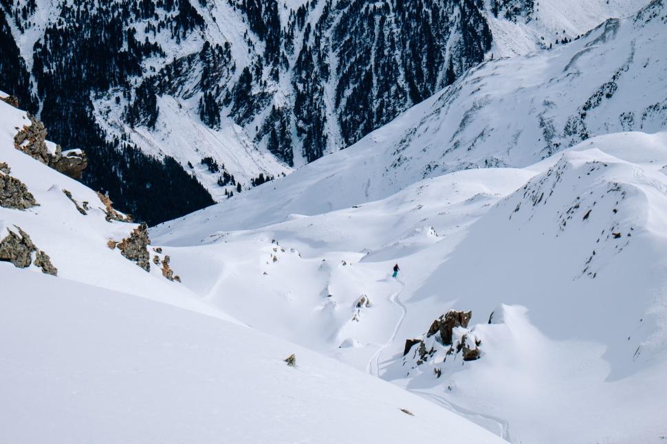Free Image of Person skiing down a snow-covered mountain range 