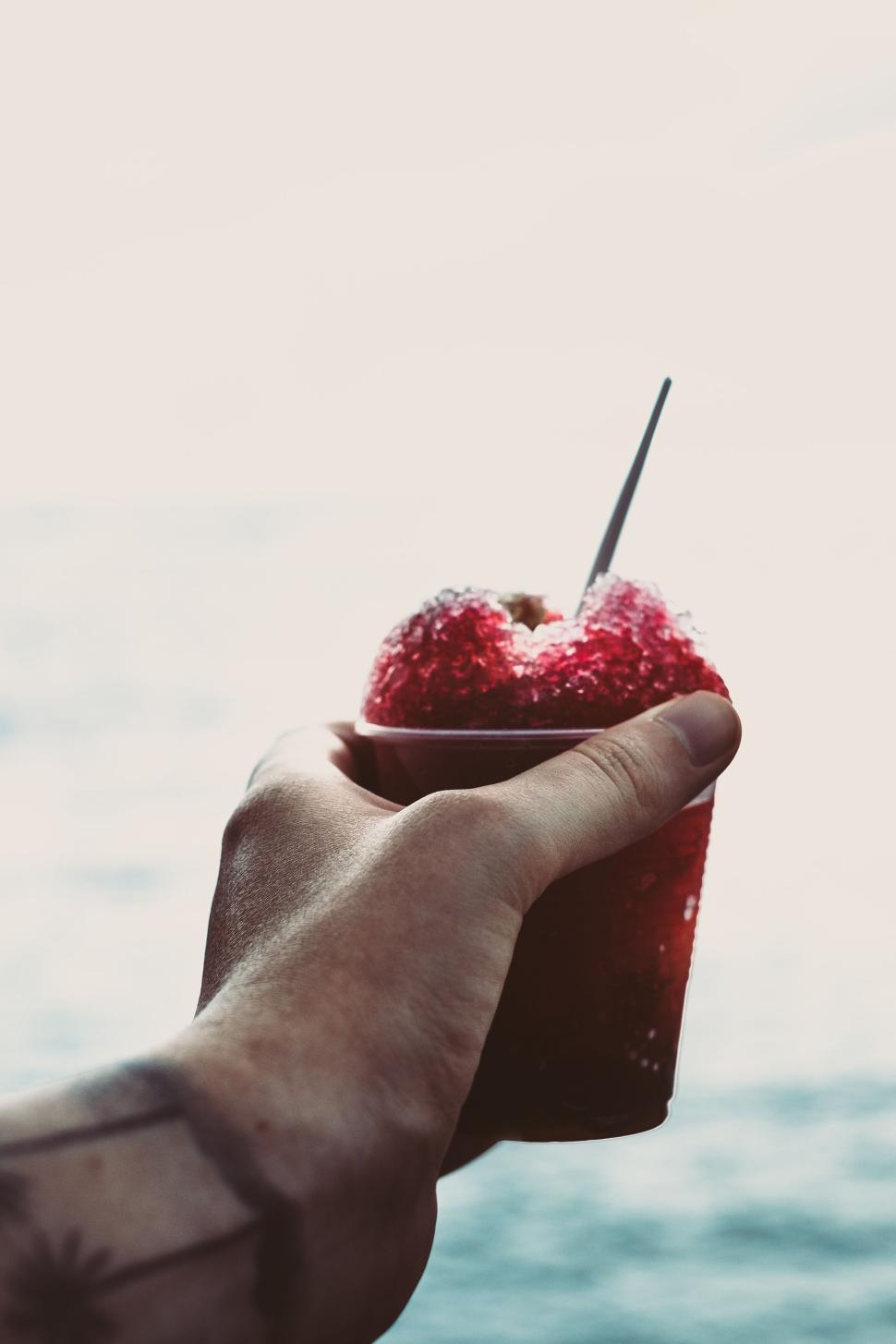 Free Image of Close-up of a person s hand holding a red snow cone 
