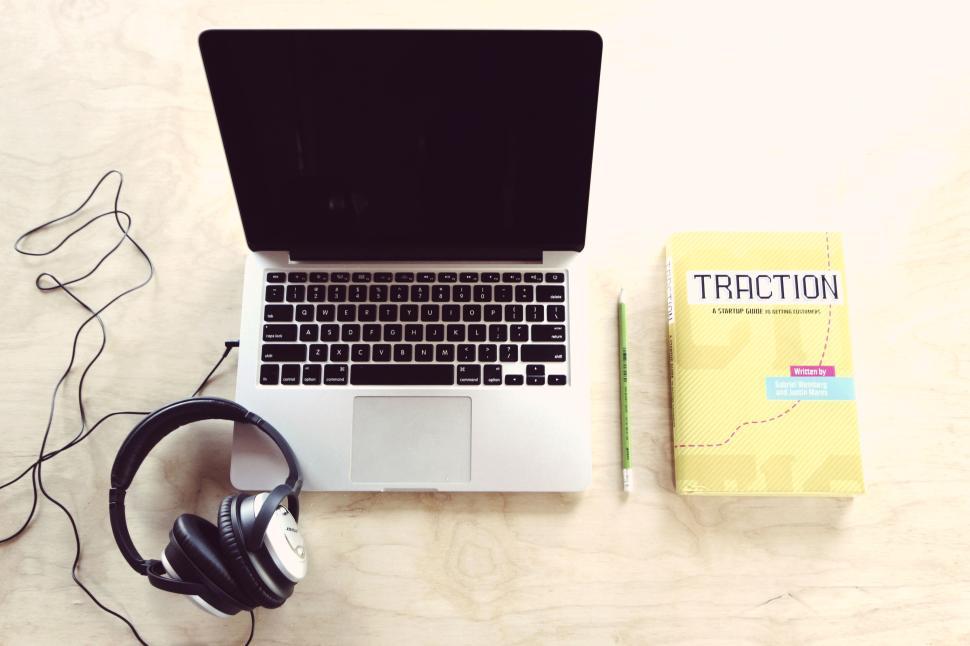 Free Image of Laptop with book and headphones on wooden table. 