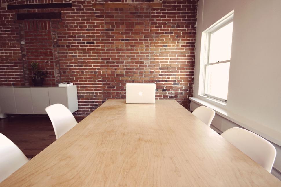 Free Image of Open laptop on large wooden table in bright room. 