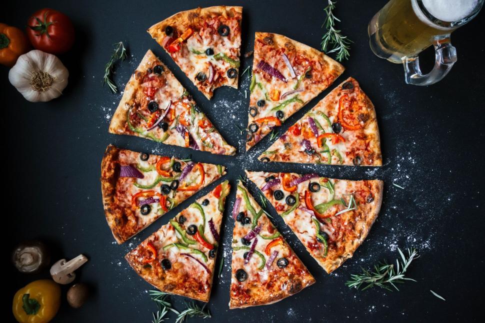 Free Image of Delicious pizza with toppings sliced and beer on table. 