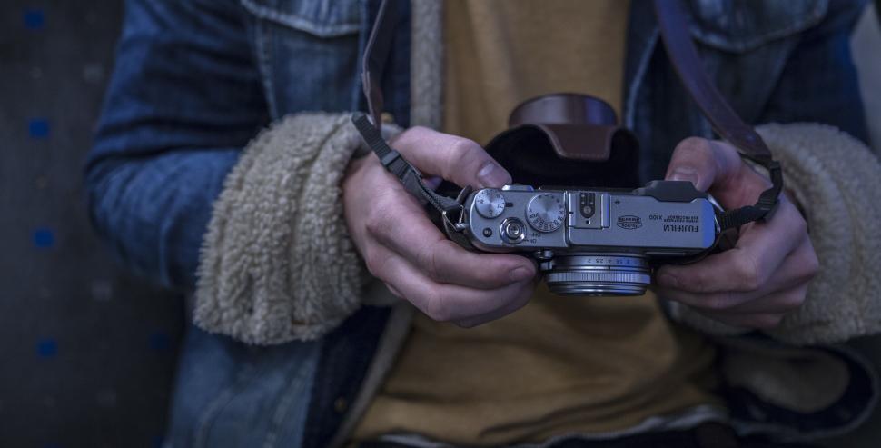 Free Image of Person holding camera with denim jacket details visible 