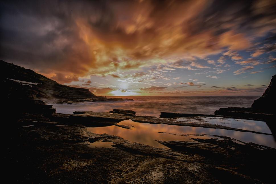Free Image of Colorful sunset over rocky coastline reflected in tidal pool 