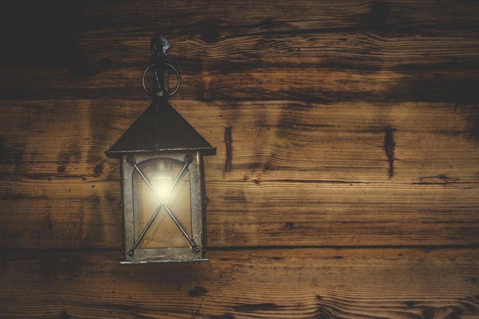 Free Image of Antique lantern glowing on rustic wooden wall 