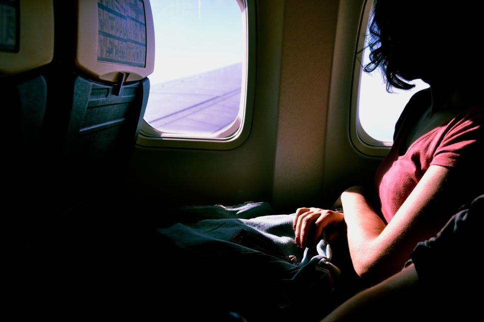 Free Image of Person sitting in an airplane near the window seat. 