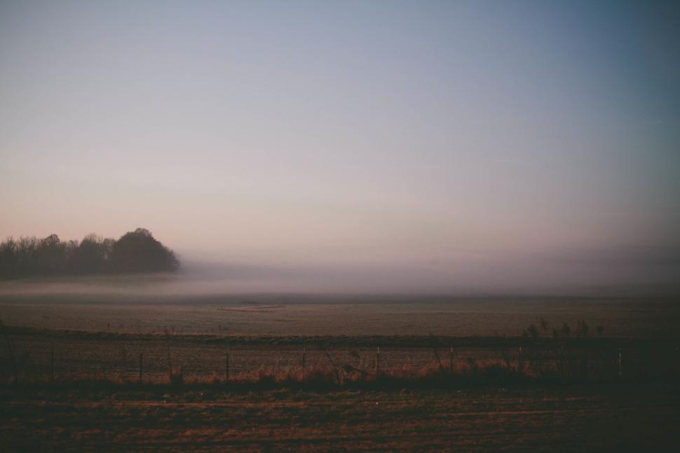 Free Image of Misty sunrise over open field with distant trees 