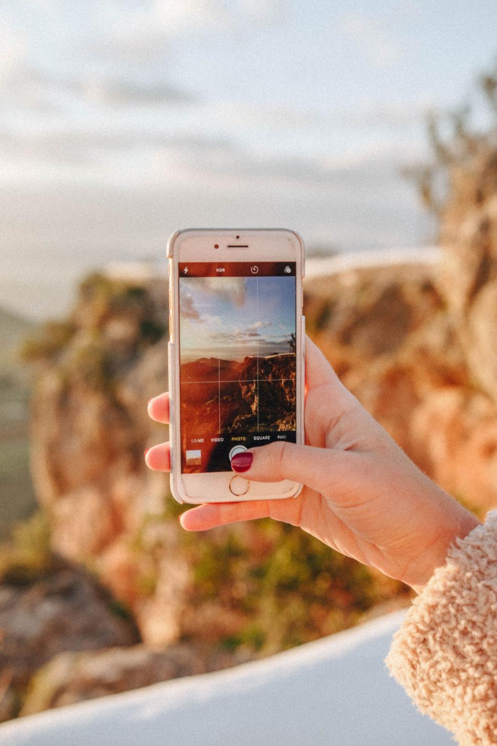 Free Image of Person holding phone capturing scenic mountain view 