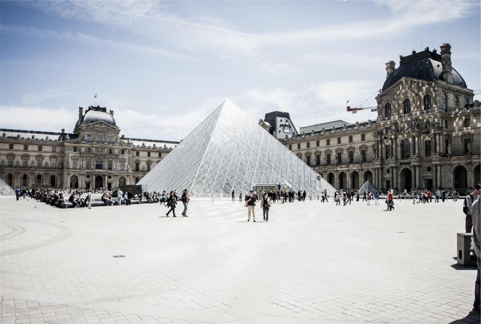 Free Image of Glass pyramid at the Louvre amidst historic buildings. 