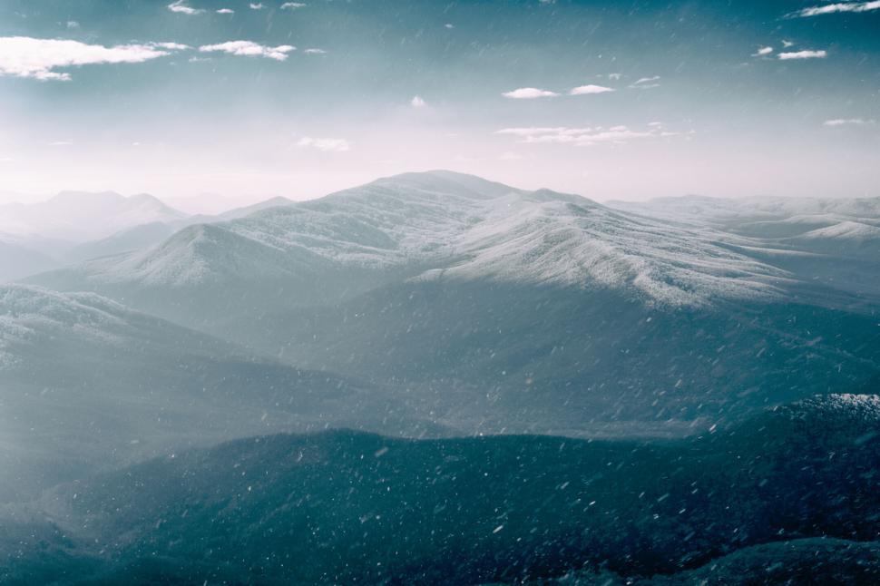 Free Image of Snow-dusted mountains under clear sky with gentle snowfall 